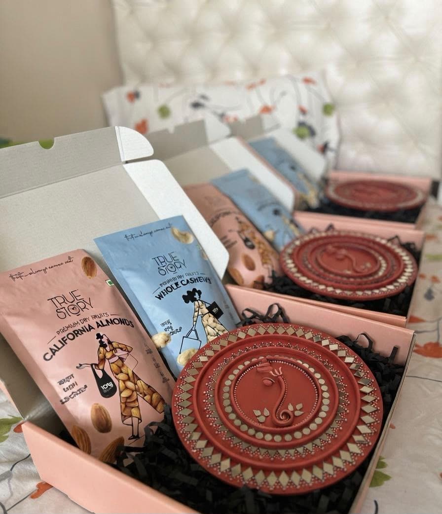 Vighnaharta Gift Box — Ganesha Lippan Wall Hanging with Dry Fruits — handmade 12-inch red lippan wall hanging with raised clay ganesha and mirror border, 100g california almonds & 100g whole cashews in gift box by Rachna Saxena