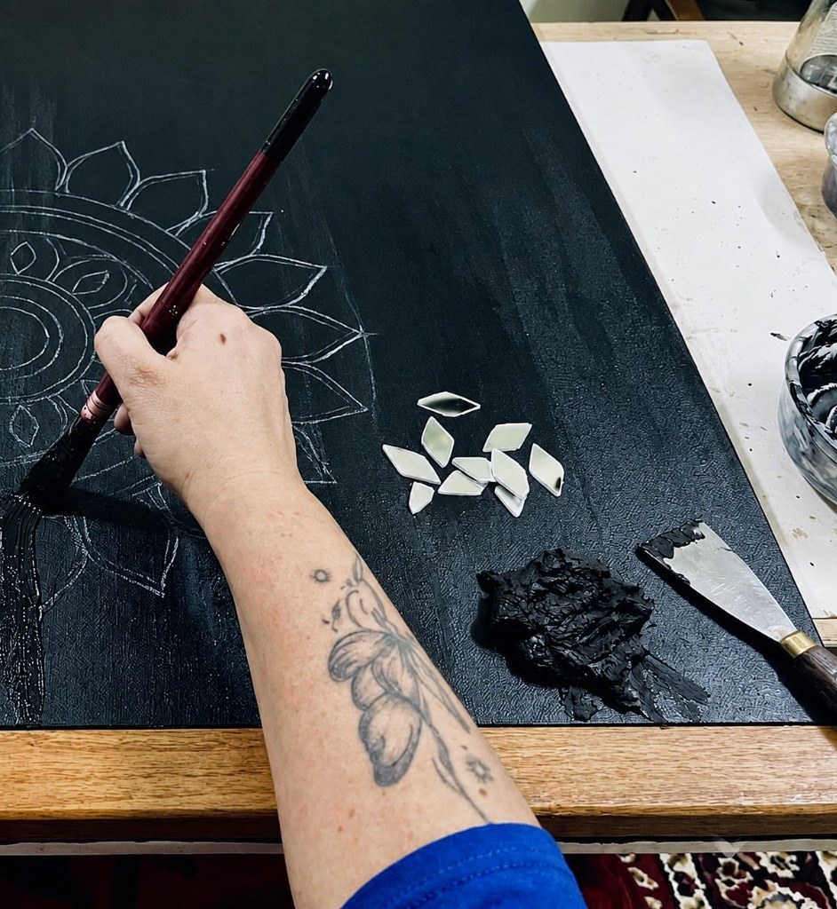 Artist handcrafting mosaic relief with diamond mirrors and paintbrush